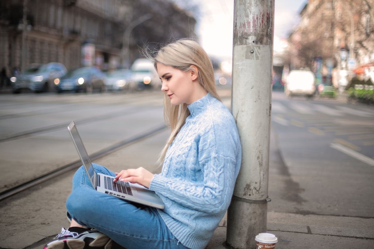Freelancer working outdoors on a laptop, exemplifying digital nomad lifestyle in a city environment.