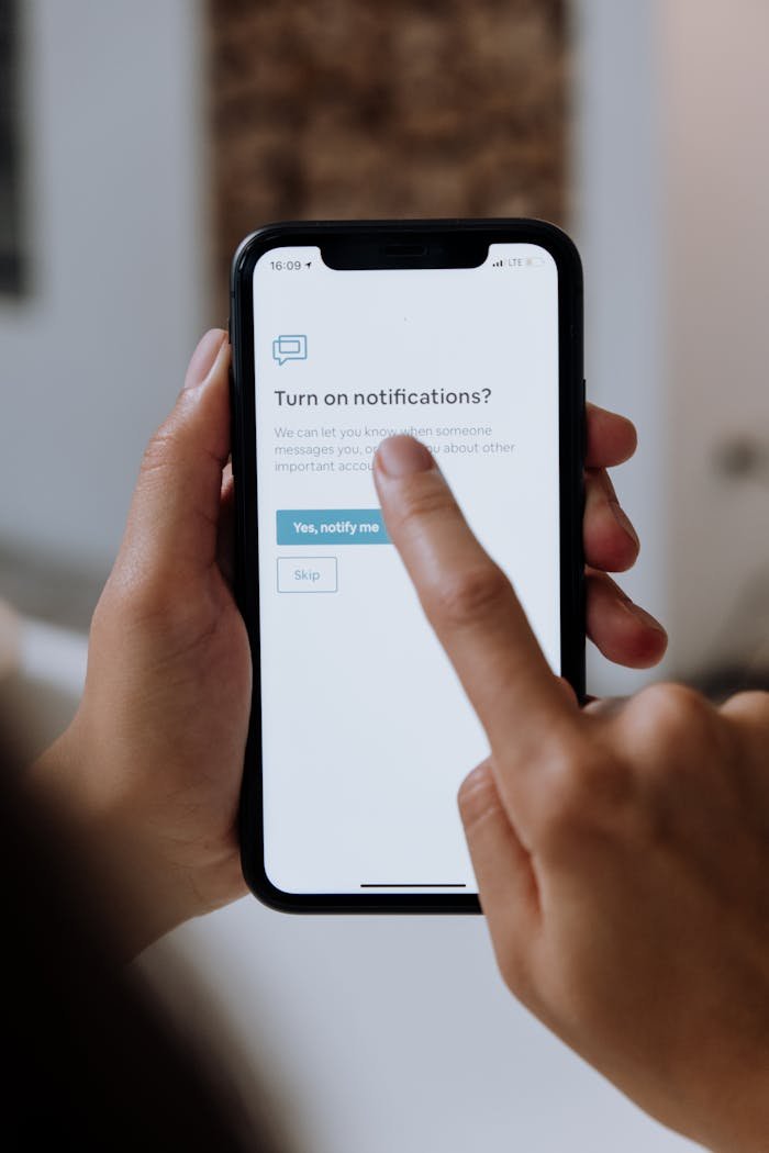 Home Close-up of hands using a smartphone for digital notification setup.
