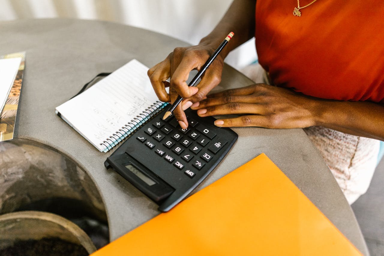 An African American woman using a calculator and notepad for budgeting.