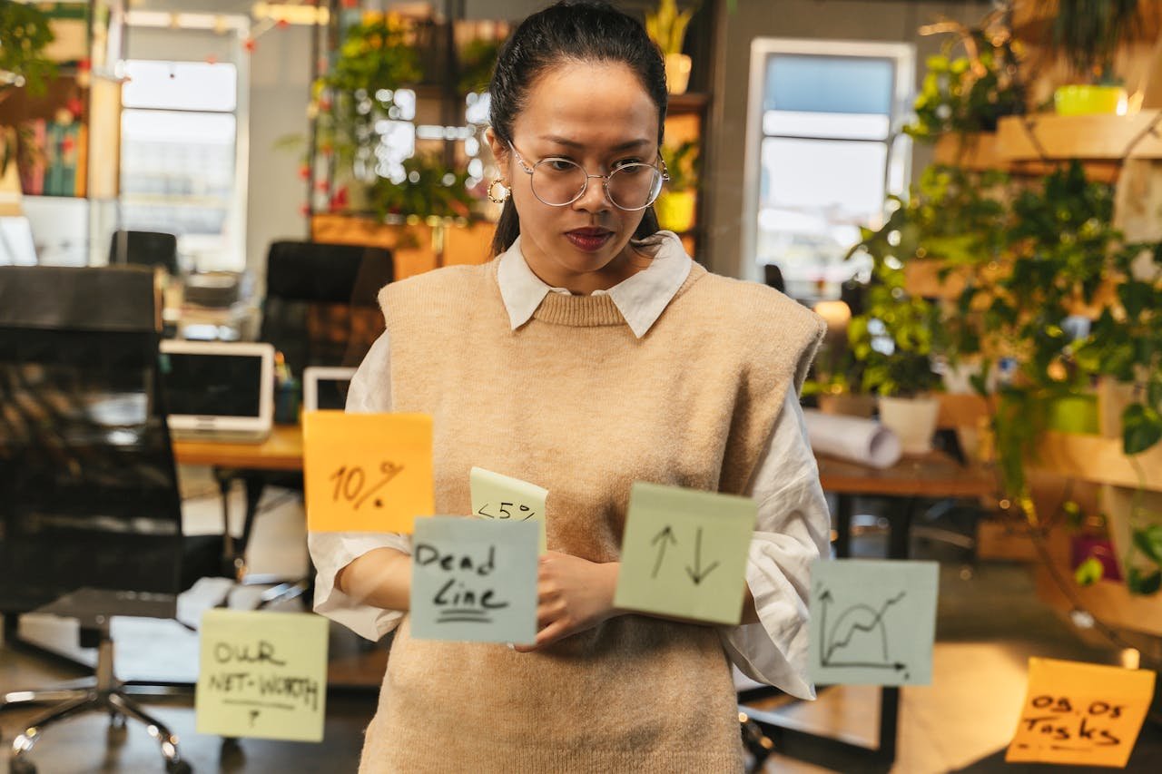 Focused woman strategizing with sticky notes in a modern office setting.
